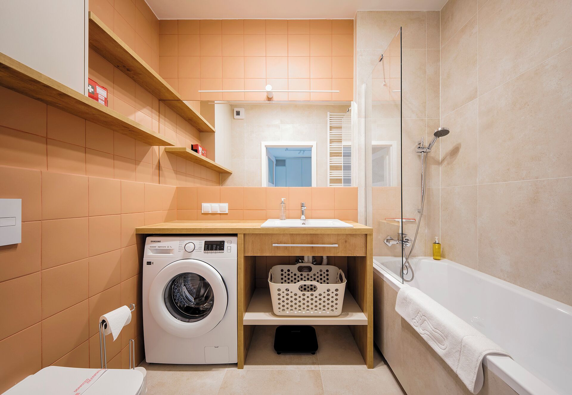 Une petite salle de bain équipée d’un lave-linge, d’un lavabo, d’une douche et de toilettes.