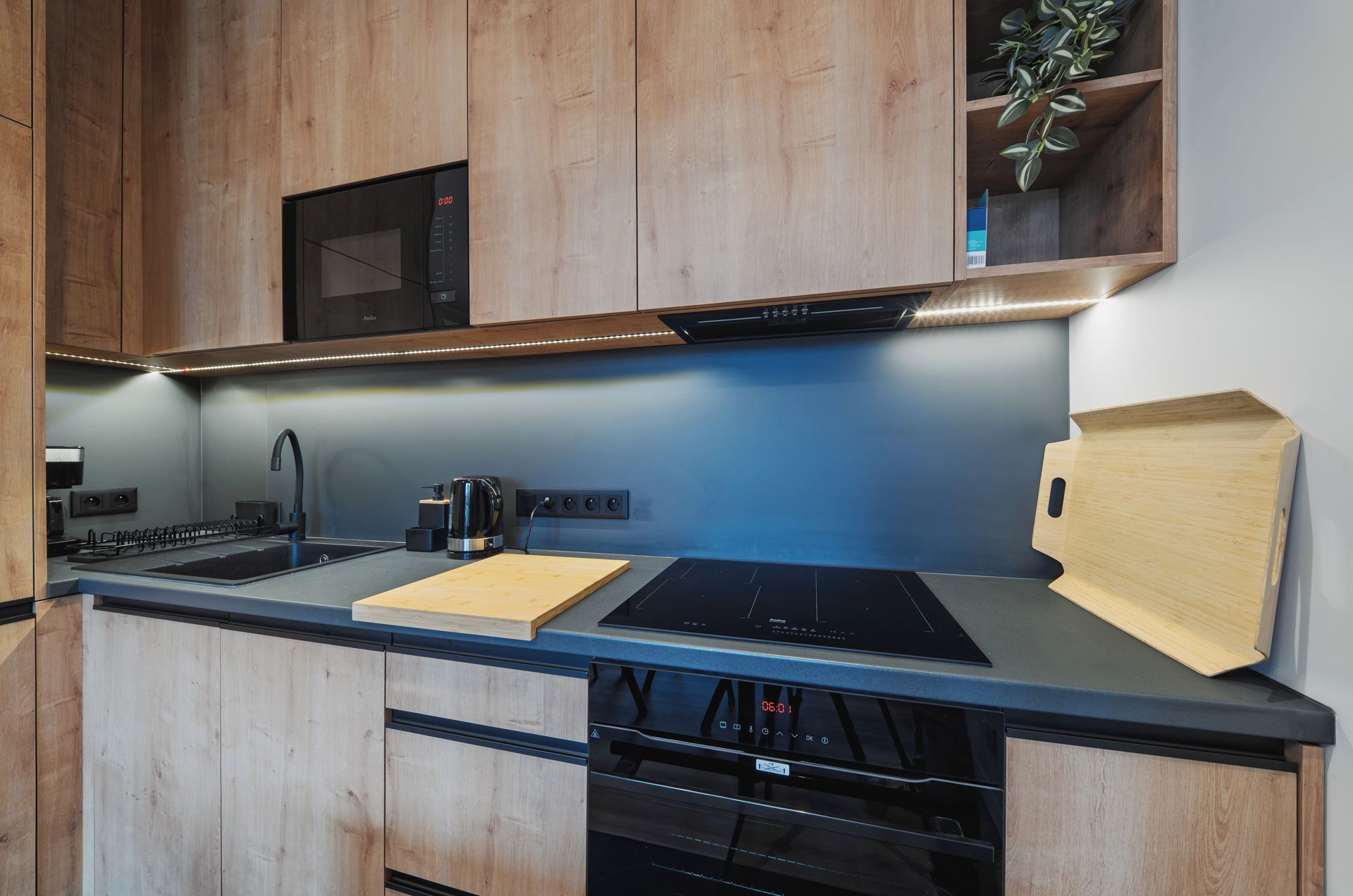 A modern kitchen with wooden cabinets, a built-in microwave, a coffee maker, and a dishwasher.