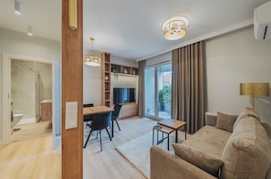 A modern living room with a sofa, a coffee table, and a dining area with a table and chairs. - RentPlanet - Apartament Dąbrowskiego (Poznań)