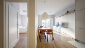 A modern kitchen with white cabinets, a wooden dining table, and orange chairs. - RentPlanet - Apartament Dąbrowskiego (Poznań)