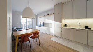 A modern kitchen with white cabinets, a wooden dining table, and orange chairs. - RentPlanet - Apartament Dąbrowskiego (Poznań)