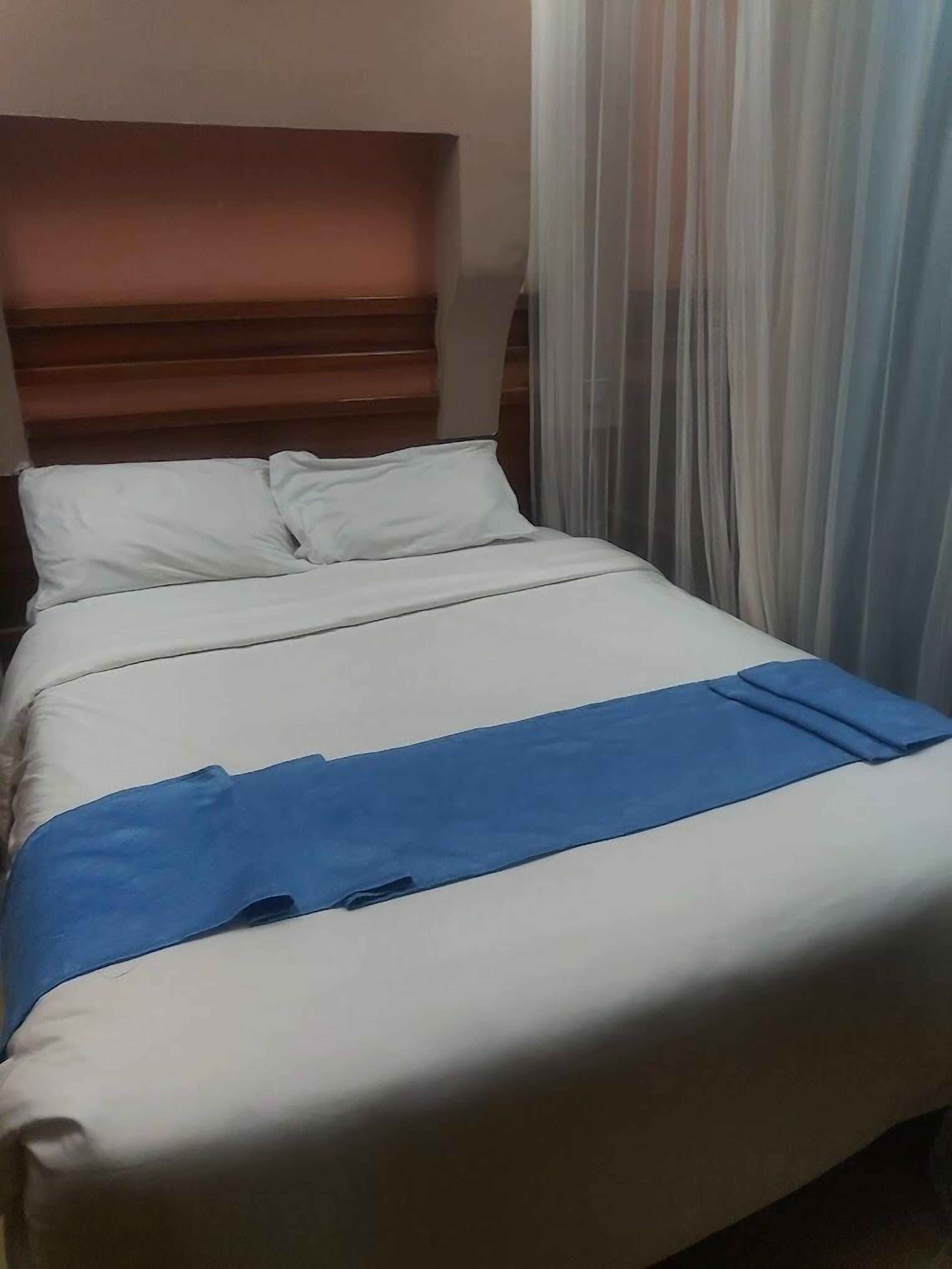 Una cama bien hecha con ropa de cama blanca y detalles azules.