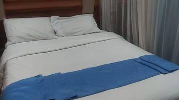 Una cama bien hecha con ropa de cama blanca y detalles azules.