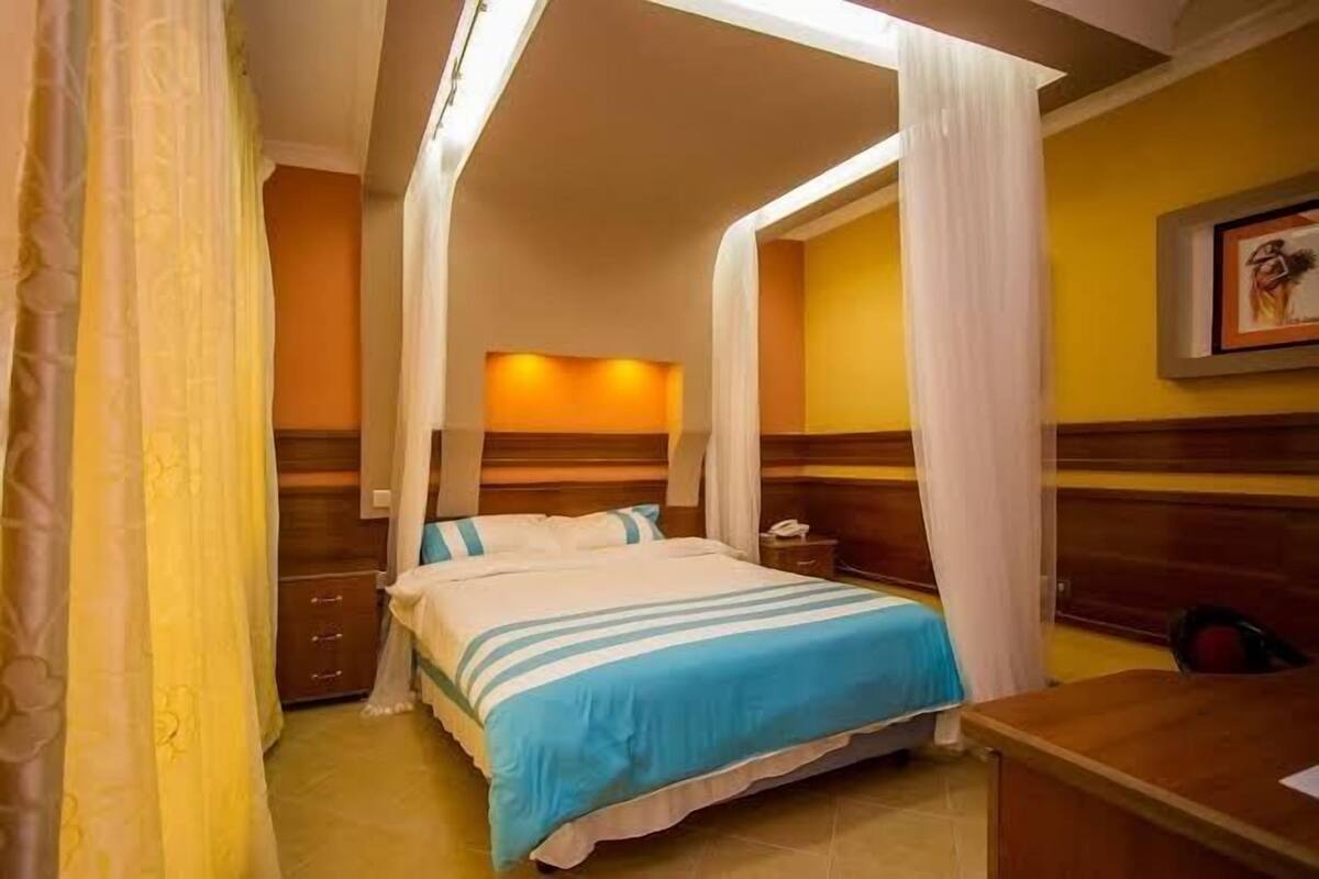 A hotel room with a bed, a desk, and a nightstand.