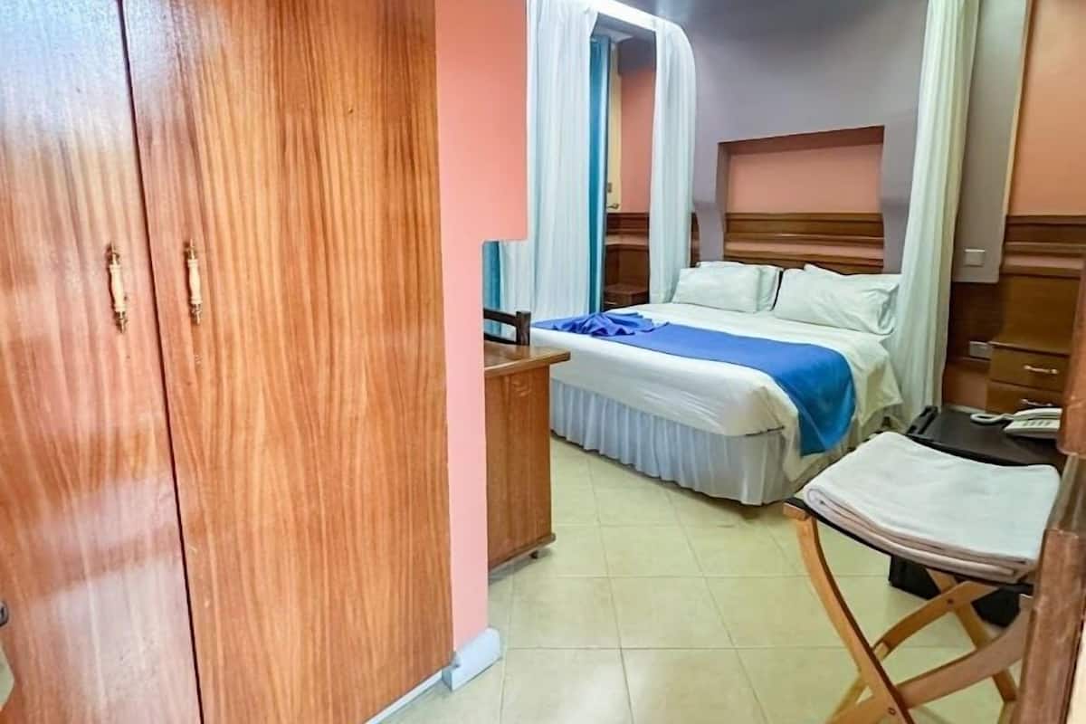A bedroom with a bed, bedside table, and a wardrobe.
