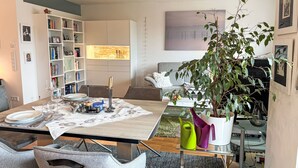 A modern living room with a dining area, a bookshelf, a sofa, and a large plant. - Ammerside by Interhome (Weilheim in Oberbayern)