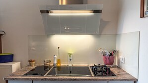 A modern kitchen with a built-in stove, a stainless steel range hood, and a granite countertop. - Ammerside by Interhome (Weilheim in Oberbayern)