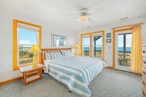 A bedroom with a bed, two bedside tables, a ceiling fan, and a view of the beach through large windows. - Oceanfront, Dog Friendly Home in Avon with Private Swimming Pool and Hot Tub (Avon)