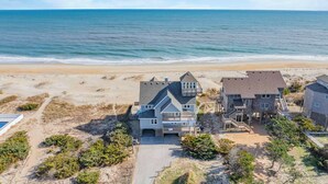 A beachfront property with a large house and a smaller building, both featuring multiple stories and balconies. - Oceanfront, Dog Friendly Home in Avon with Private Swimming Pool and Hot Tub (Avon)