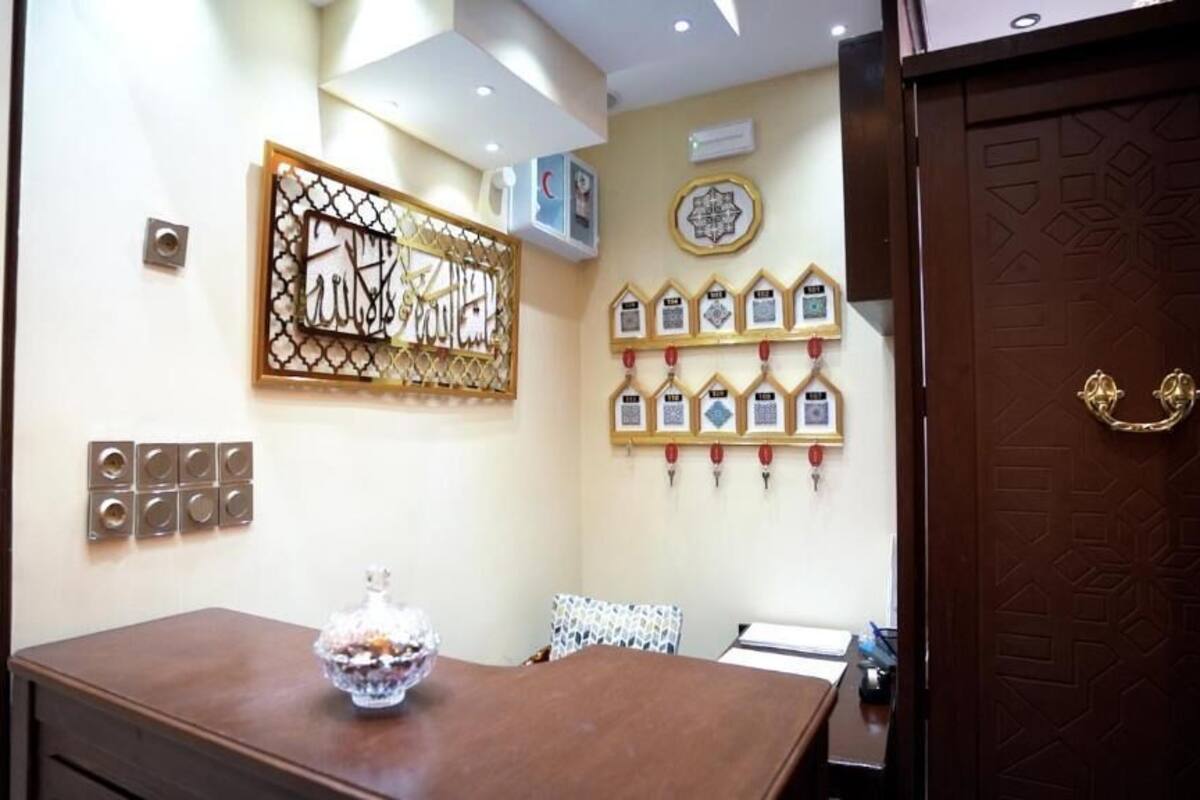A room with a wooden table, a decorative wall piece, framed certificates, and a patterned door.