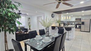 A modern kitchen with stainless steel appliances, a dining area with a marble table, and a ceiling fan. - #39 The Farmington House (Port Richey)