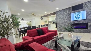 A modern living room with a red sofa, a glass coffee table, and a fireplace. - #39 The Farmington House (Port Richey)