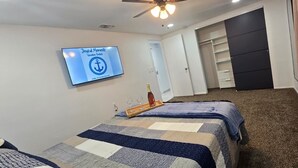 A bedroom with a bed, a TV displaying 'Joyful Moments Vacation Rentals', a wooden tray with glasses, and a closet. - #39 The Farmington House (Port Richey)