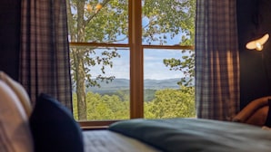 Un dormitorio con un ventanal que ofrece vistas a un paisaje boscoso.