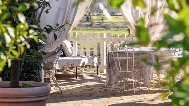 Une terrasse extérieure avec une clôture blanche, des tables recouvertes de nappes à motifs floraux et des chaises.