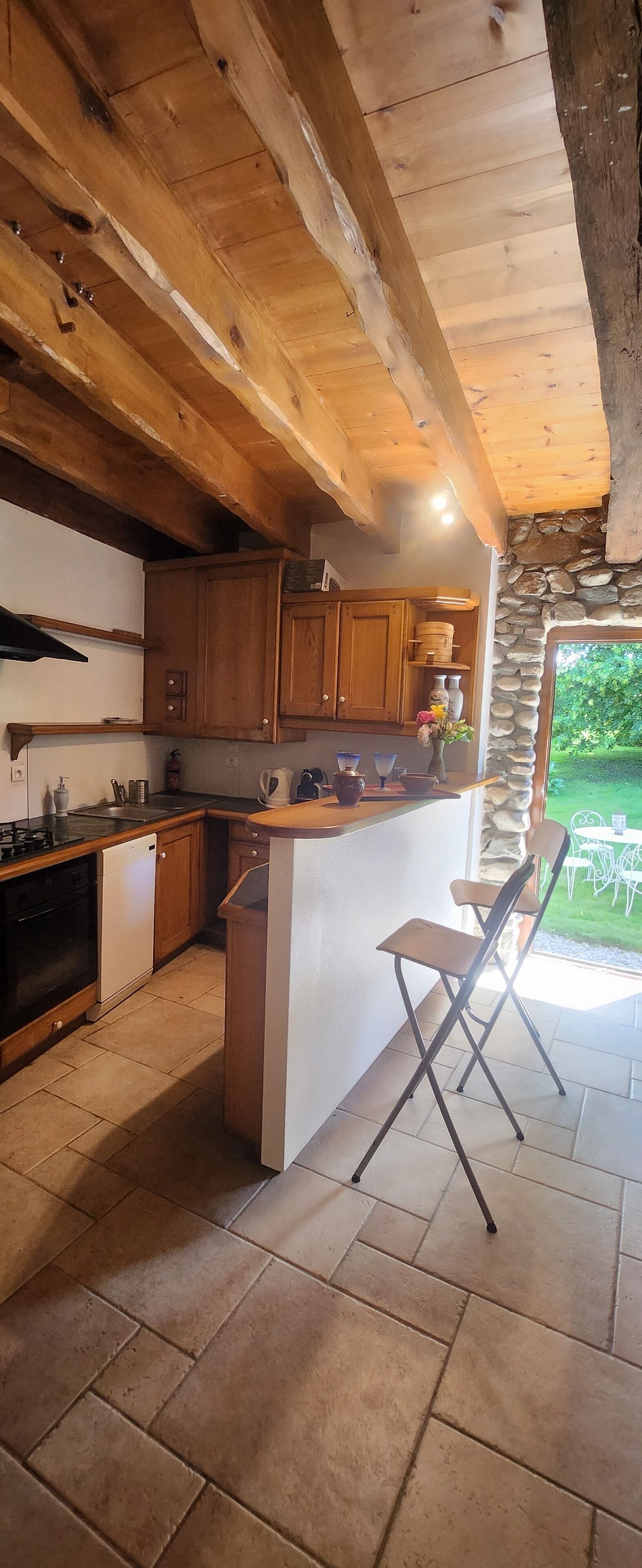 Eine Küche mit Holzausstattung, einer Steinwand und Blick ins Freie.