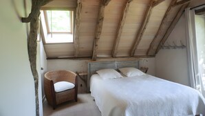 A bedroom with a wooden ceiling, a bed with white bedding, a wicker chair, and a window. - La Sylve Guest Room with Private Terrace, Shared Garden and Wi-Fi (Marcilhac sur Célé)