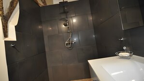 A modern bathroom with dark tiles, a shower, and a white sink. - La Sylve Guest Room with Private Terrace, Shared Garden and Wi-Fi (Marcilhac sur Célé)