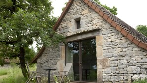 A stone building with a sloped roof, a glass door, and a small window.