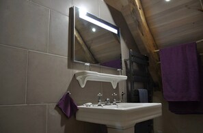 Een badkamer met een witte wastafel, een spiegel en een paarse handdoek.