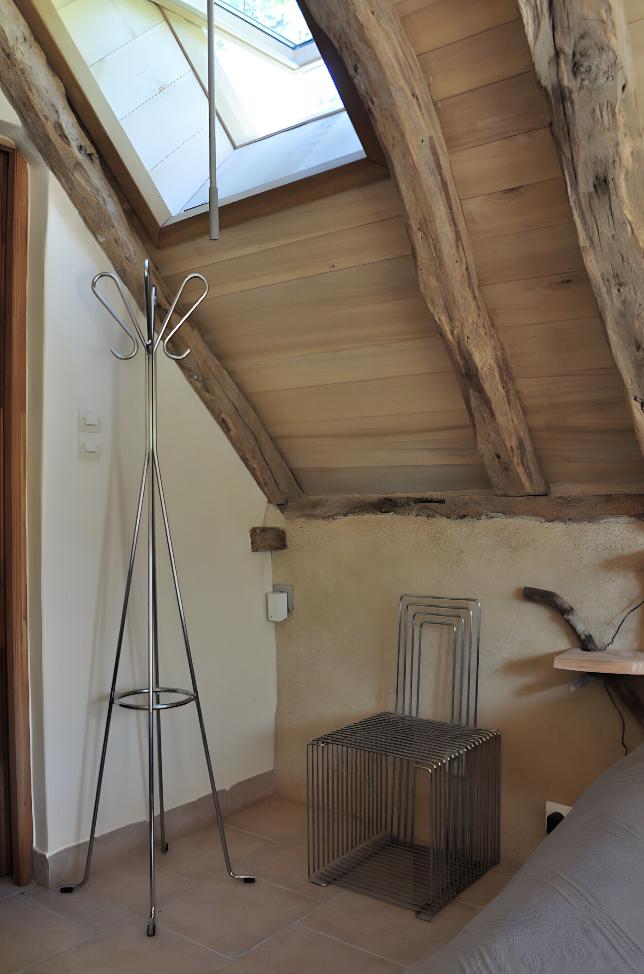 Une pièce dotée d’un plafond en pente, d’un puits de lumière, d’un support métallique et d’une étagère métallique.