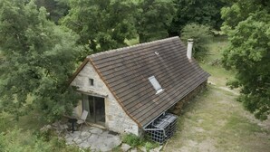 A stone building with a sloped roof, a small door, and a fenced area.