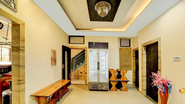 A spacious hallway with a wooden bench, a refrigerator, and a staircase leading to another room. - Collection O Vrindavan Palace Colony (Indore)
