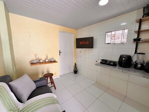 Een knus verblijf met kitchenette, een bank, een eettafel en een aan de muur bevestigde televisie.