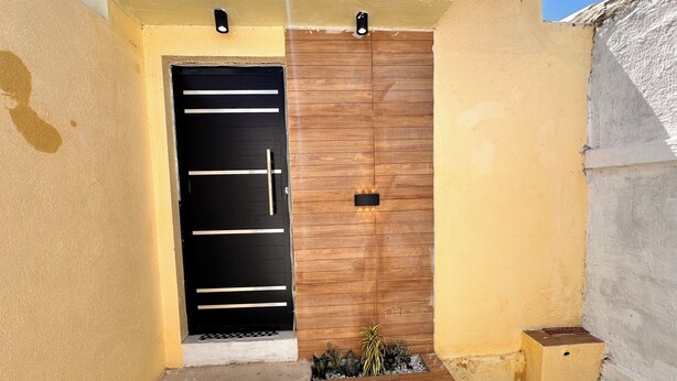 A black door with horizontal handles and a wooden panel door with a small black plate. - AirBNBusiness Maracanaú (Maracanau)