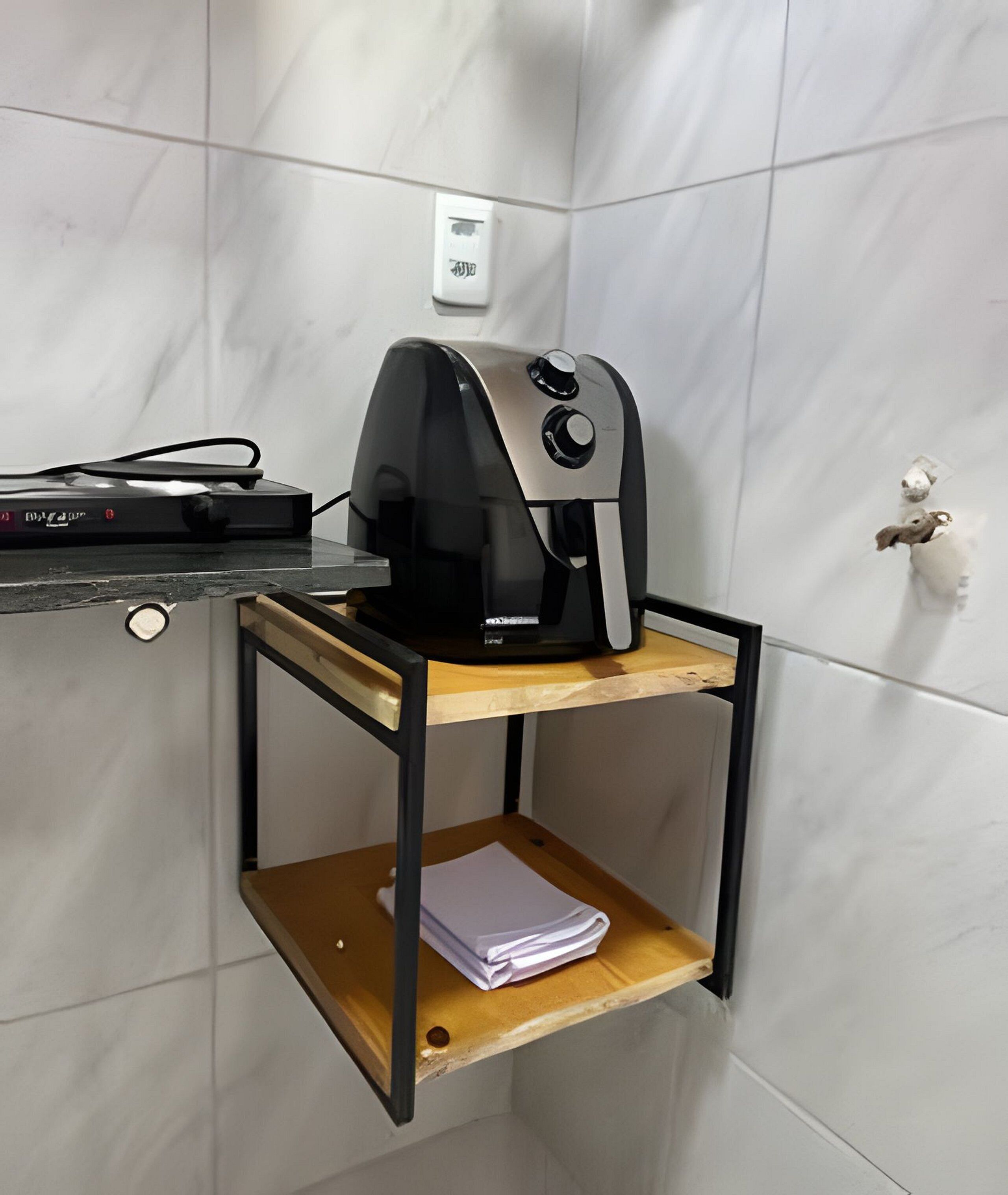 A corner of a room with a coffee maker on a shelf, a power outlet, and a door with a lock.