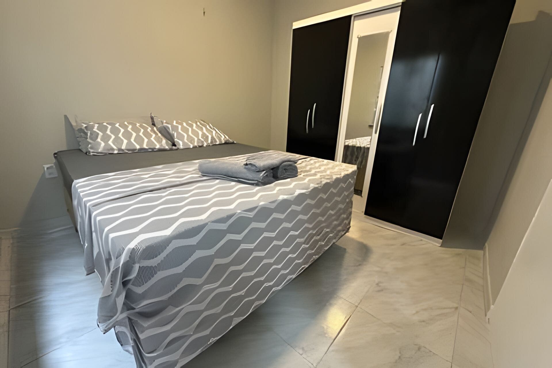 A bedroom with a bed, a wardrobe, and a mirror.