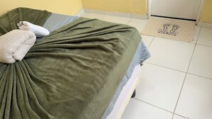 A bed with a green blanket, a white pillow, and a blue pillow.