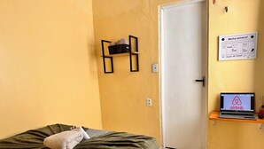 A room with a bed, a laptop on a shelf, and a calendar on the wall. - AirBNBusiness Maracanaú (Maracanau)
