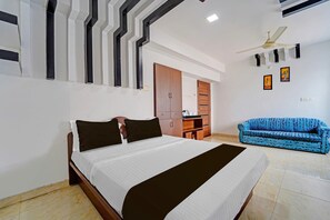 Un dormitorio con cama, sofá azul, armario y ventilador de techo.