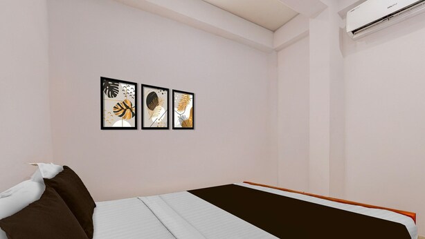 Ein Schlafzimmer mit einem Bett, Kissen und drei gerahmten Kunstwerken an der Wand.