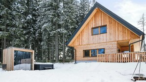 Una cabaña de madera con balcón, rodeada de árboles cubiertos de nieve.