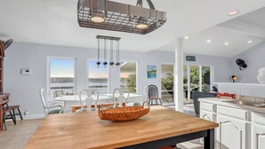 Une cuisine moderne avec des meubles blancs, une table à manger en bois et un luminaire suspendu.