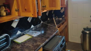 Una cocina con armarios de madera, encimera de granito, lavadora y puerta con ventanal.