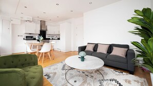 Een moderne woonkamer met een grijze bank, een groene fauteuil en een ronde salontafel.