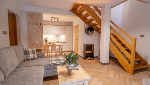 Un salon moderne avec un escalier en bois, un canapé, une table basse et une cuisine en arrière-plan.