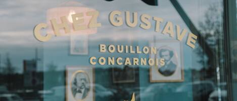 Una ventana con el texto "CHEZ GUSTAVE BOUILLON CONCARNOIS" y un pequeño icono de pájaro.