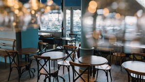 Interno di un ristorante con tavoli e sedie rotonde, una colonna blu e una vista dalla finestra.
