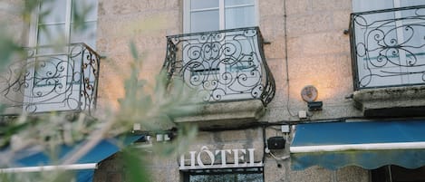 A hotel with ornate iron balcony railings, a sign indicating it is a hotel, and a visible restaurant sign above.