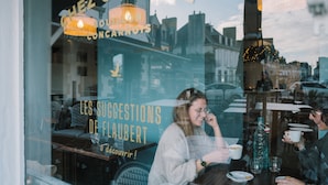 Un caffè con vista sulla città, con un cartello che riporta “Chez Gustave” e “Les Suggestions de Flâubert”.