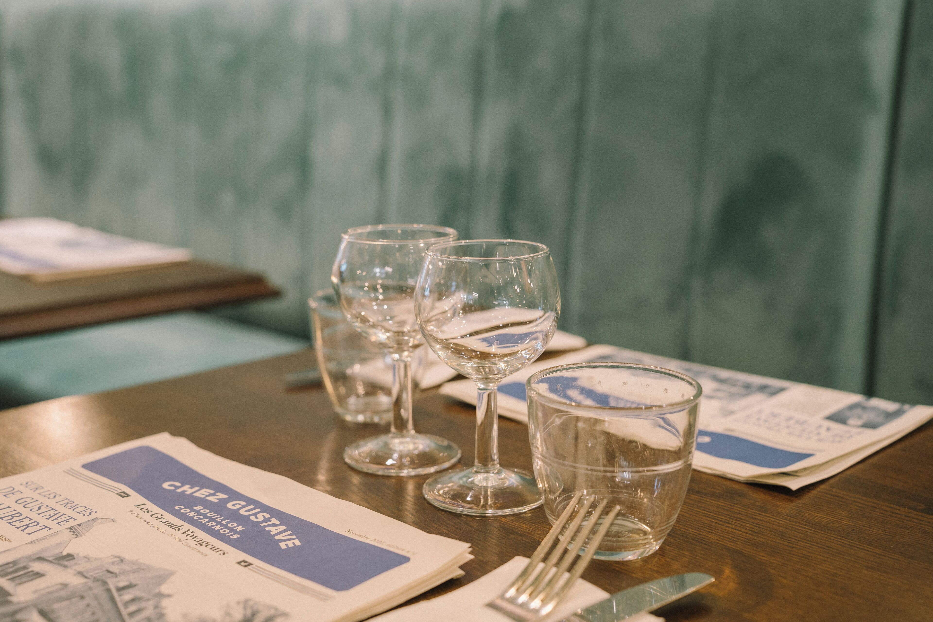 A table with a menu, wine glasses, and a glass of water.