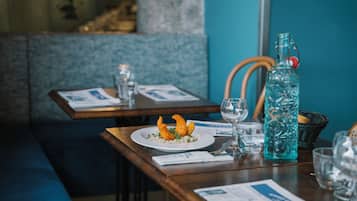 A restaurant setting with a table set for two, including plates of food, glasses, and a water bottle.