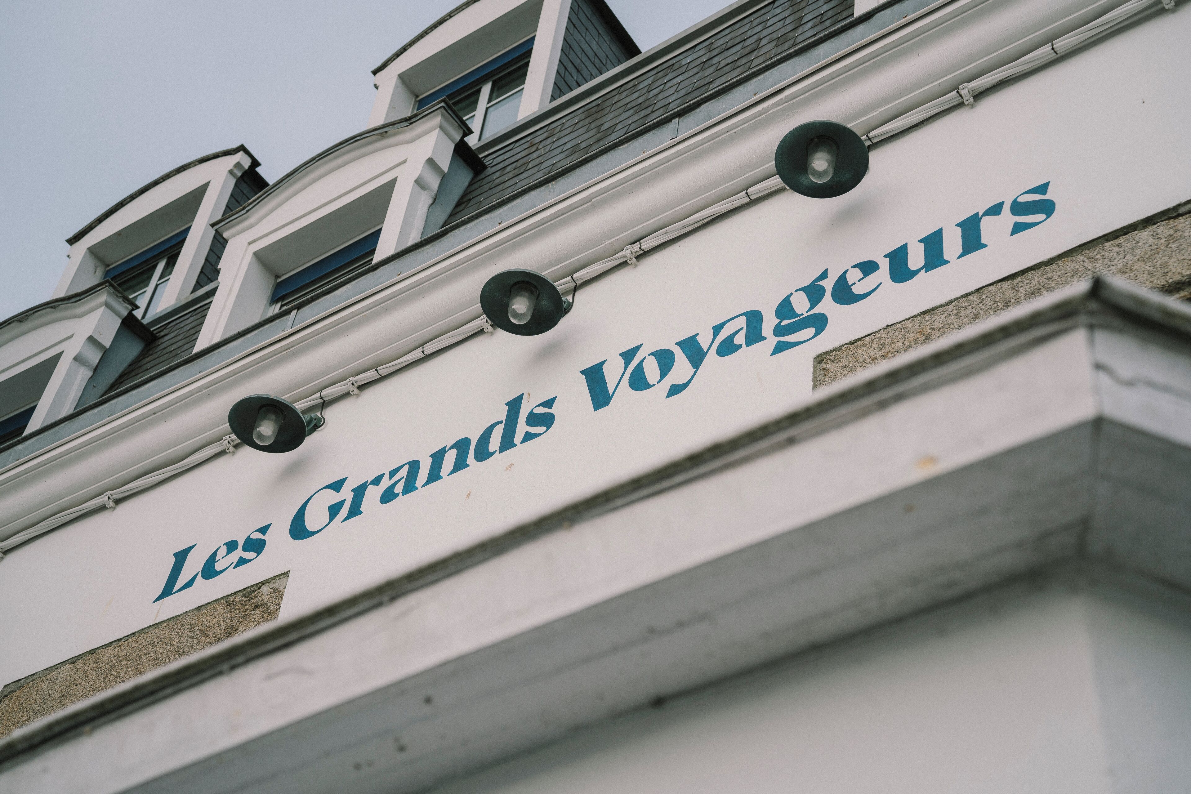 Fachada de un edificio con el letrero "Les Grands Voyageurs", que indica un hotel u establecimiento similar.