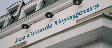 Fachada de un edificio con el letrero "Les Grands Voyageurs", que indica un hotel u establecimiento similar.