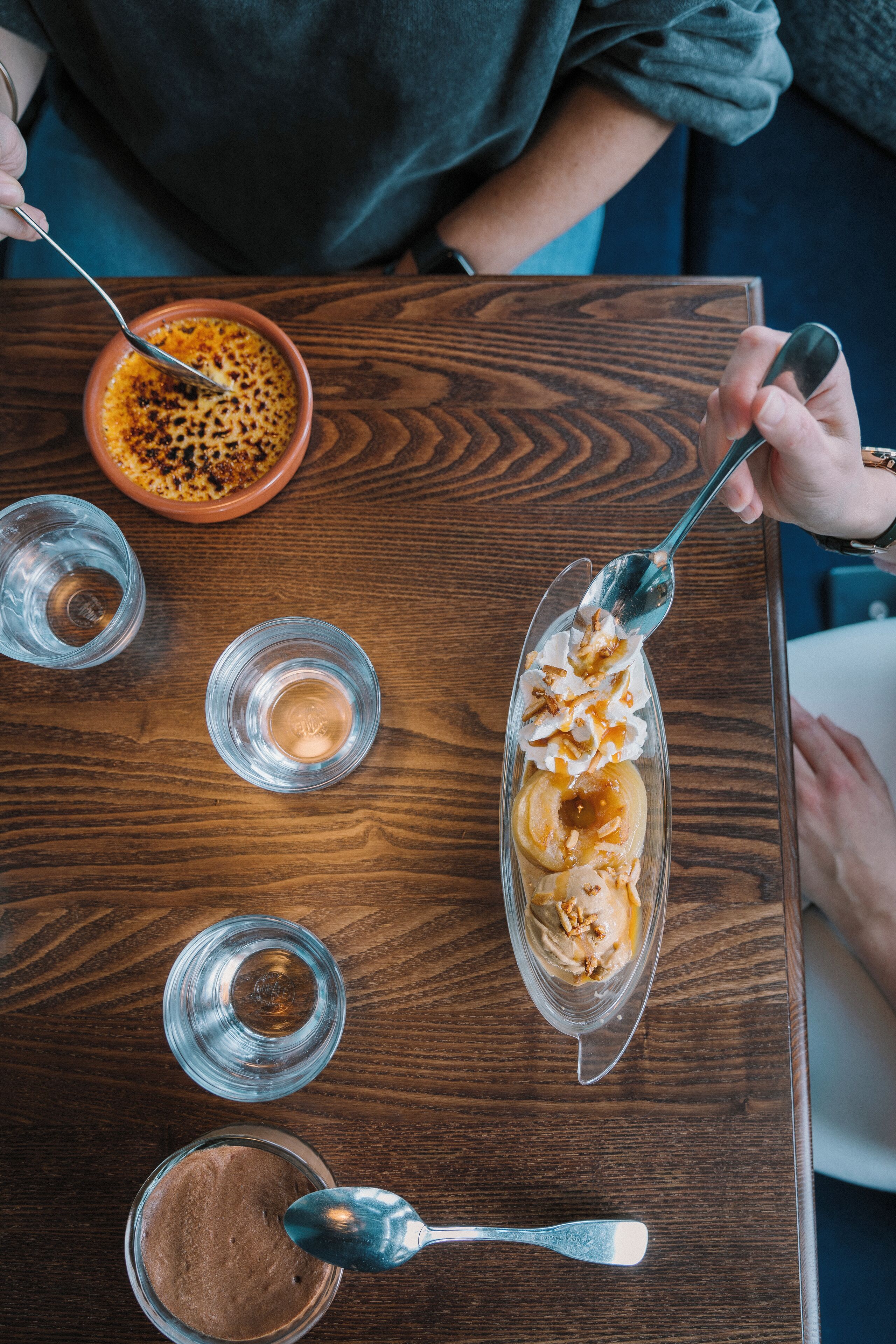 Una mesa de madera con un plato de postre, un bol y dos vasos.