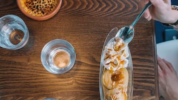Una mesa de madera con un plato de postre, un bol y dos vasos.